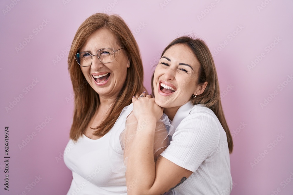 Hispanic mother and daughter wearing casual white t shirt smiling and laughing hard out loud because funny crazy joke. Hispanic mother and daughter wearing casual white t shirt smiling and laughing hard out loud because funny crazy joke.