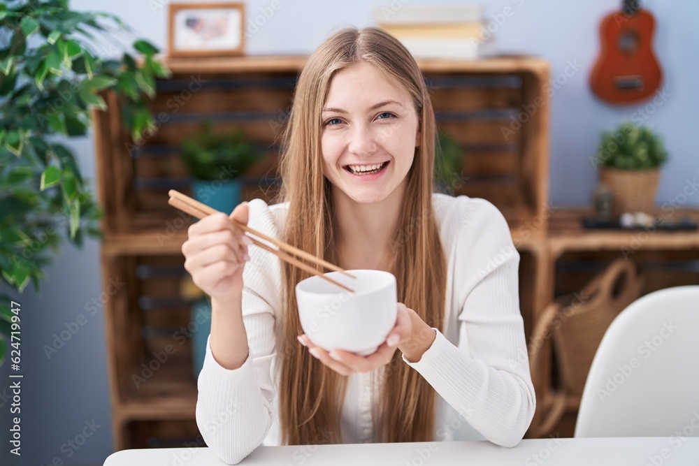Young caucasian woman eating asian food using chopsticks smiling and laughing hard out loud because funny crazy joke. Young caucasian woman eating asian food using chopsticks smiling and laughing hard out loud because funny crazy joke.