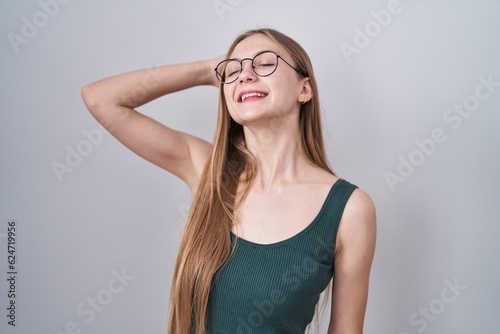 Young caucasian woman standing over white background smiling confident touching hair with hand up gesture, posing attractive and fashionable