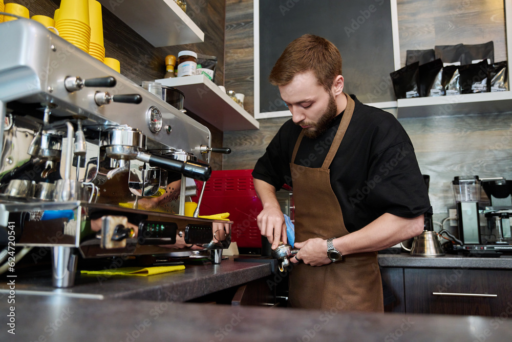 Young male barista preparing coffee in coffee shop Young male barista preparing coffee in coffee shop