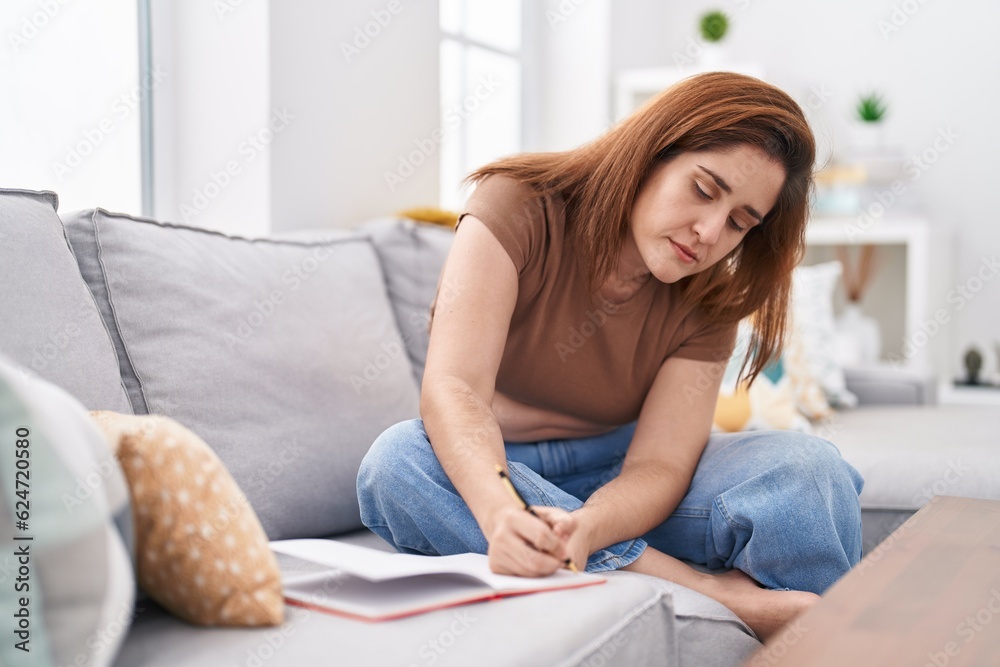 Young woman writing on notebook at home Young woman writing on notebook at home