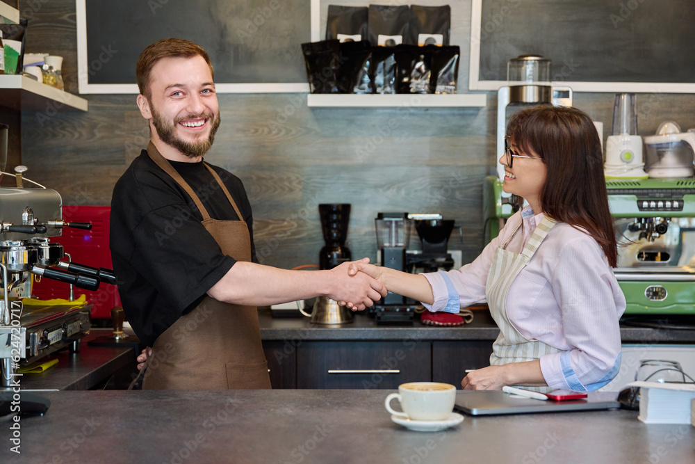 Colleagues, partners, man and woman shake hands, in coffee shop Colleagues, partners, man and woman shake hands, in coffee shop