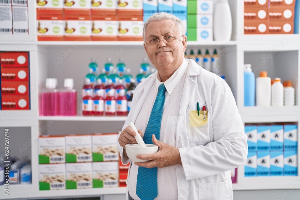 Middle age grey-haired man pharmacist smiling confident make mixture at pharmacy Middle age grey-haired man pharmacist smiling confident make mixture at pharmacy