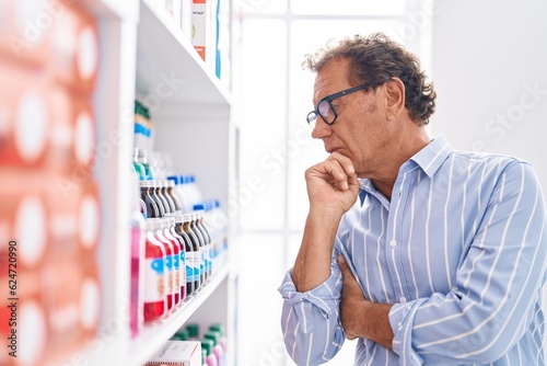 Middle age man customer looking medicine on shelving at pharmacy