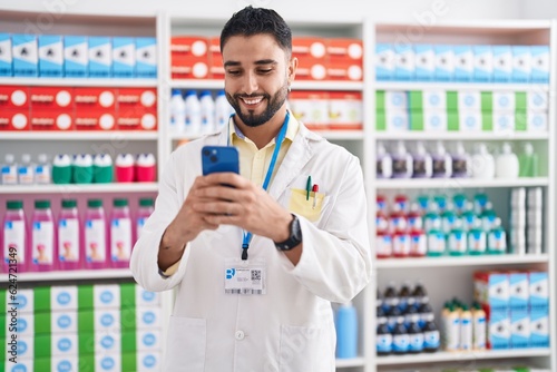 Young arab man pharmacist using smartphone working at pharmacy © Krakenimages.com