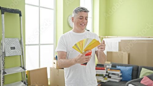 Young caucasian man smiling confident holding color test at new home