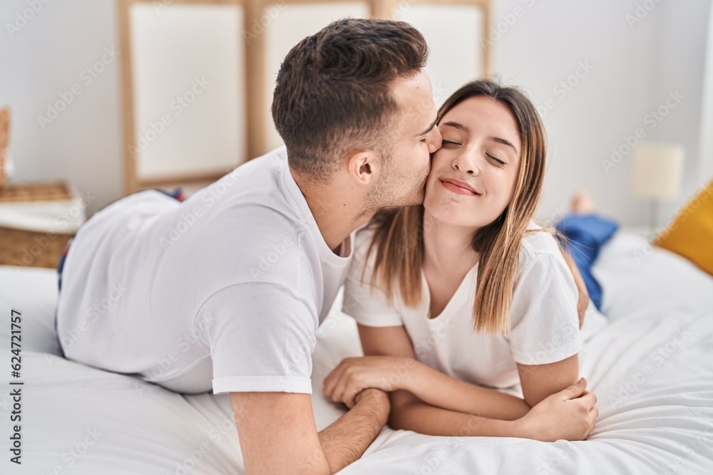 Man and woman couple lying on bed hugging each other and kissing at bedroom Man and woman couple lying on bed hugging each other and kissing at bedroom