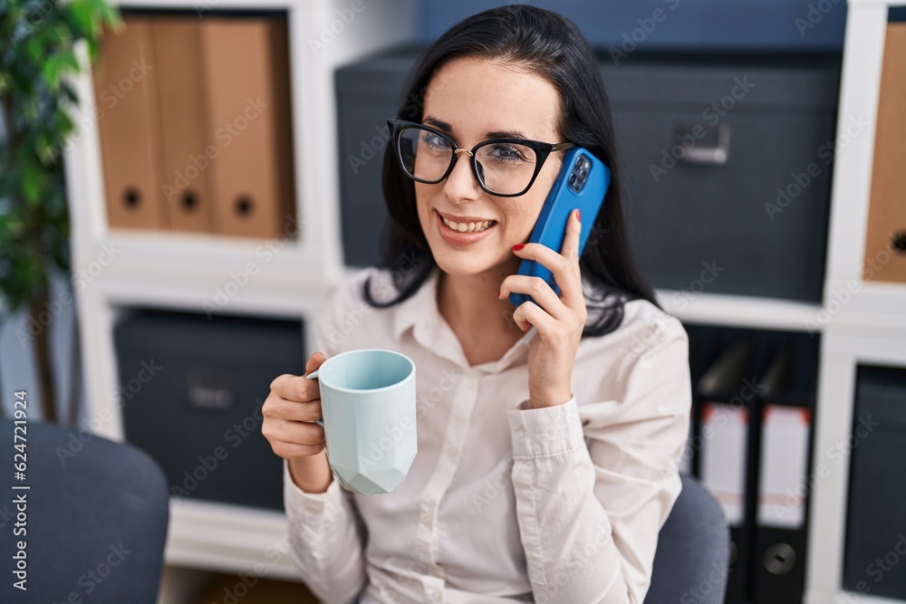 Young caucasian woman business worker talking on smartphone drinking coffee at office Young caucasian woman business worker talking on smartphone drinking coffee at office