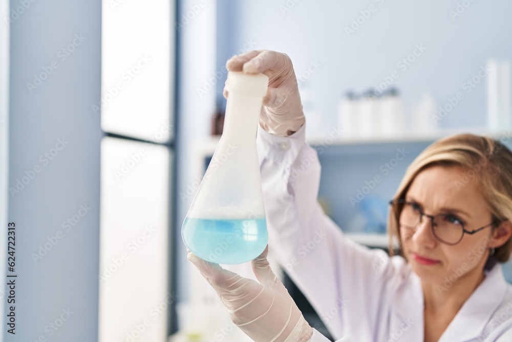 Fototapeta premium Young blonde woman scientist holding test tube at laboratory