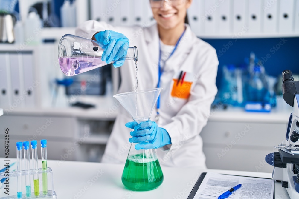 Young hispanic woman scientist measuring liquid at laboratory Young hispanic woman scientist measuring liquid at laboratory