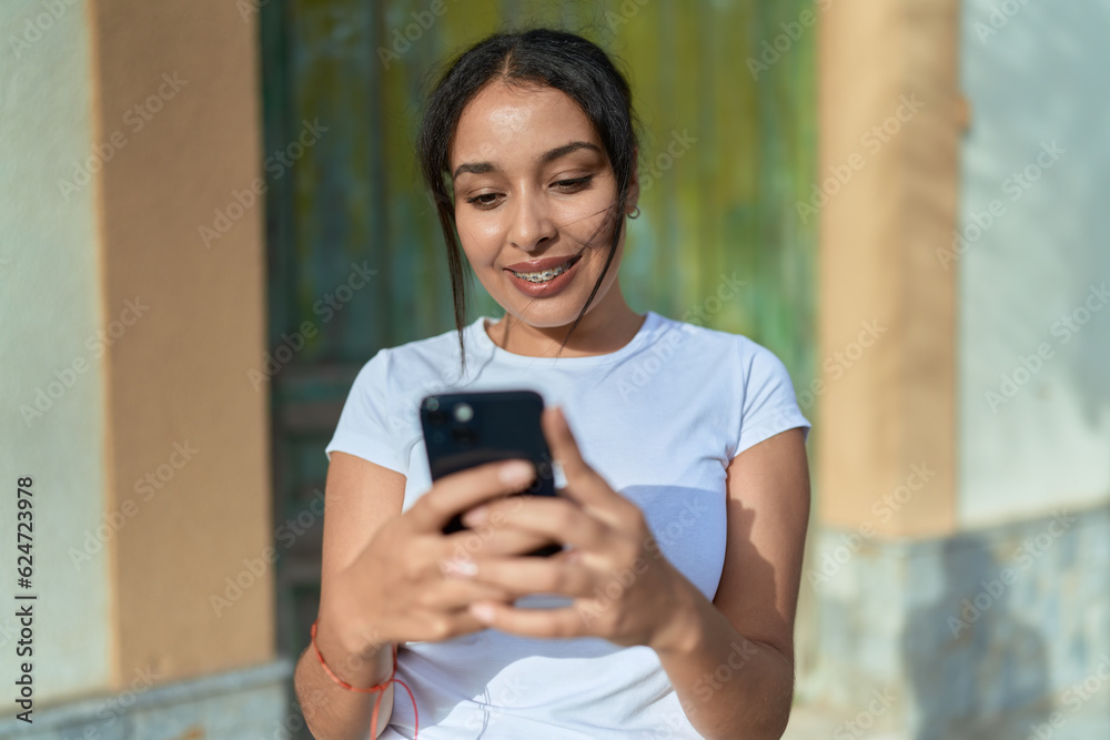 Young arab woman smiling confident using smartphone at street