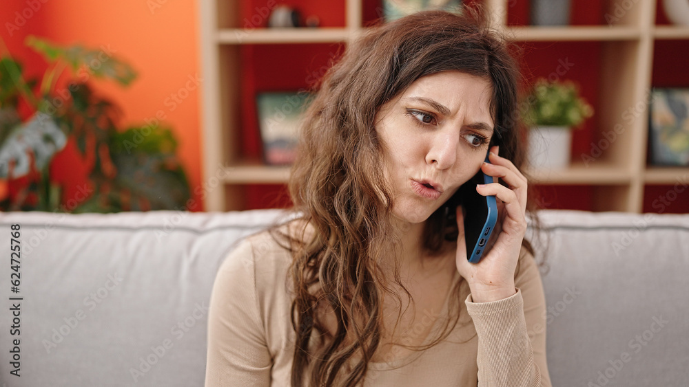 Young beautiful hispanic woman talking on smartphone upset at home Young beautiful hispanic woman talking on smartphone upset at home