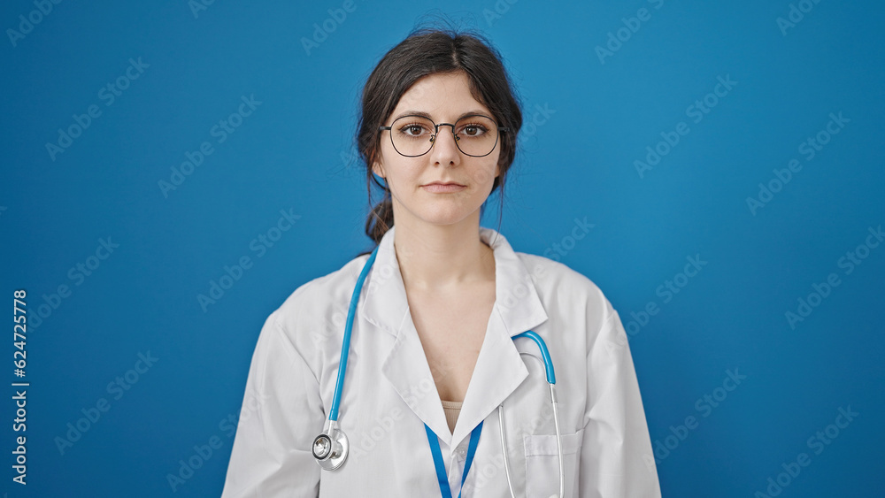 Young beautiful hispanic woman doctor standing with serious expression over isolated blue background Young beautiful hispanic woman doctor standing with serious expression over isolated blue background