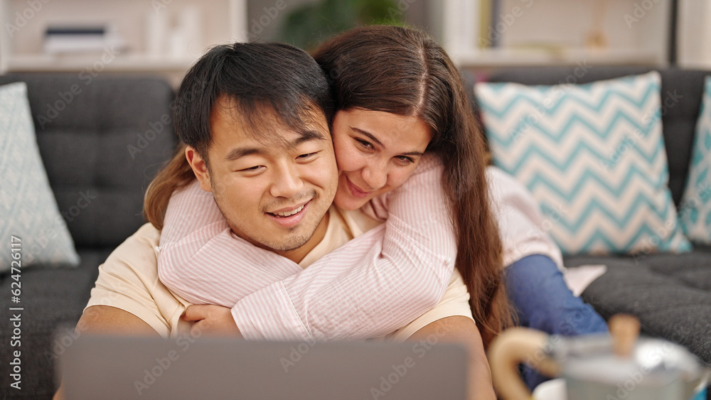 Man and woman couple using laptop hugging each other at home Man and woman couple using laptop hugging each other at home