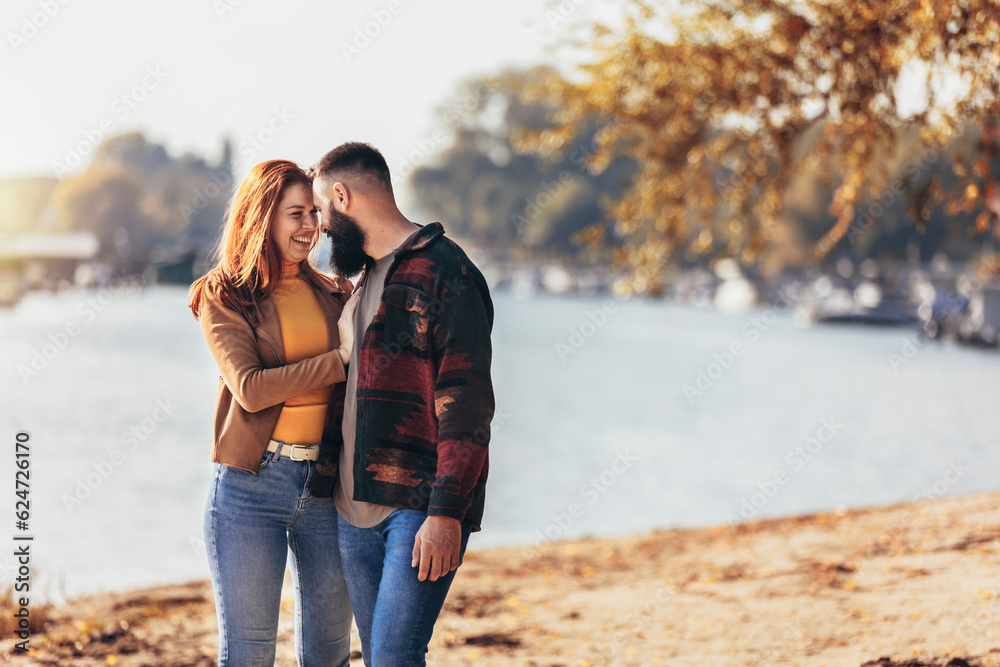 Fototapeta premium Happy young couple in love holding hands and walking on coast near river.