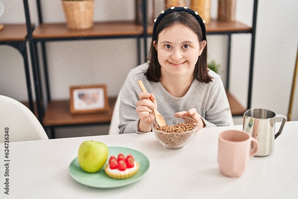 Young woman with down syndrome smiling confident having breakfast at home