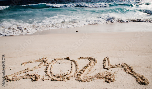 2024 written in white sand on tropical beach  happy New Year