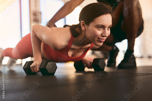 Fototapeta Naklejka Na Ścianę i Meble -  Strong sportswoman doing push ups with dumbbells in gym