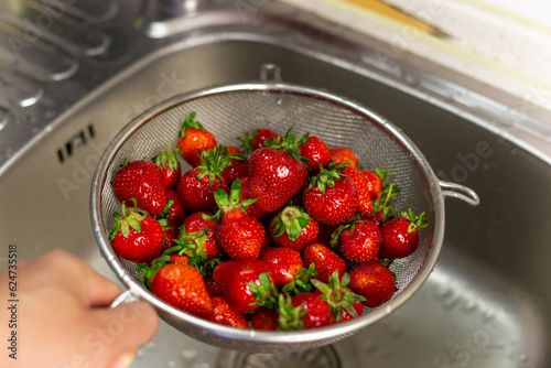 Canvastavla Delicious strawberries in metal basket rinsed with water in kitchen sink
