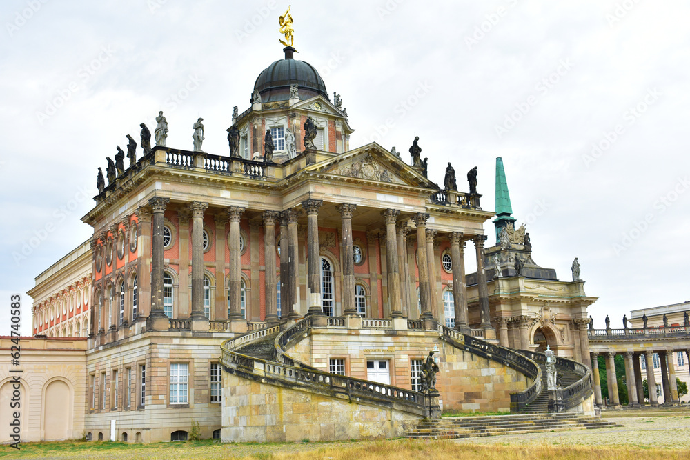 Old building with columns, statues,  dome and wide staircase with cracked dirty walls in cloudy weather. Ancient royal palace. Potsdam, Germany, August 2022 