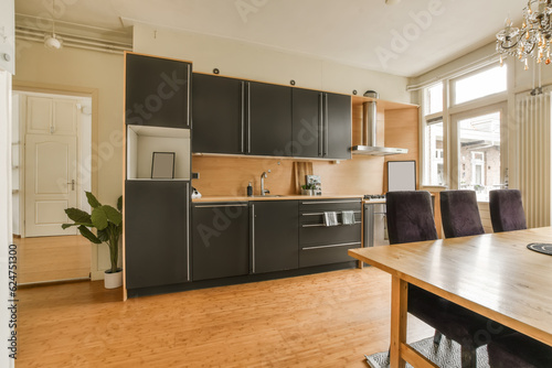 a kitchen and dining area in a house with wood floors, black cabinets, white walls and wooden flooring