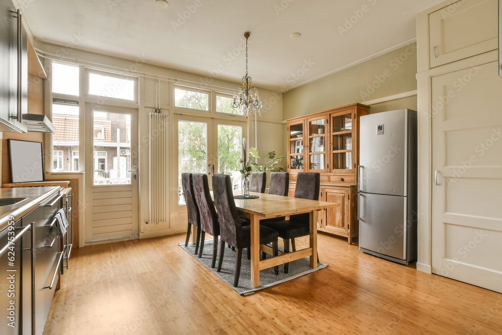 Fototapeta premium a kitchen and dining area in a house with wood flooring, white walls and doors open to the outside