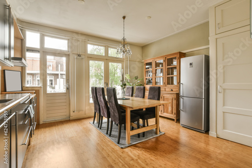 a kitchen and dining area in a house with wood flooring  white walls and doors open to the outside
