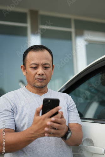 Portrait of Asian man talking on phone while in front of office