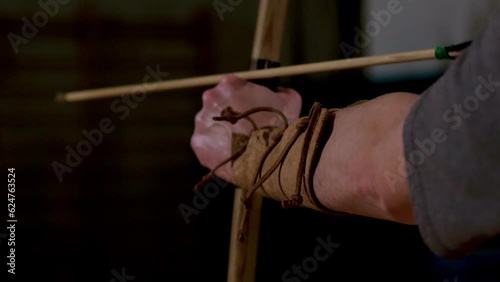 archer tends yew wood bow to shoot an arrow