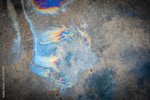 Oil spill on asphalt in the form of a stain. Abstract background from motor oil, gas or petrol spilled on asphalt.