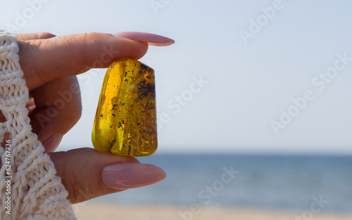 Fototapeta Naklejka Na Ścianę i Meble -  A natural, polished Baltic ambers on a sandy beach in the woman hand. Kolobrzeg, Poland.