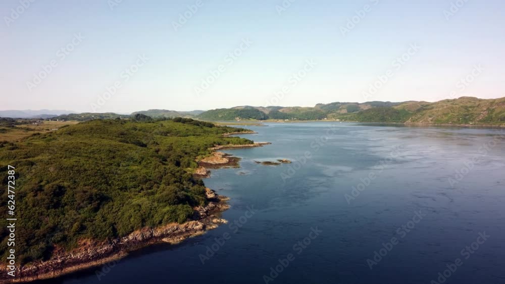 A beautiful drone shot following a Scottish island coastline, which is completely deserted apart from a few boats in the background. Shot on the Isle of Luing in Scotland in the middle of summer. A beautiful drone shot following a Scottish island coastline, which is completely deserted apart from a few boats in the background. Shot on the Isle of Luing in Scotland in the middle of summer.