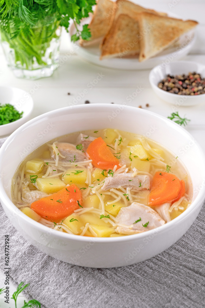 Chicken soup with noodles and vegetables in white bowl on a wooden background. Chicken soup with noodles and vegetables in white bowl on a wooden background.