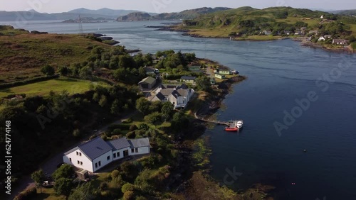A beautiful drone shot following a Scottish island shoreline panning up to reveal boats, holiday properties and the rest of the Island’s waterways, including a ferry crossing. Shot on ilse of Luing photo