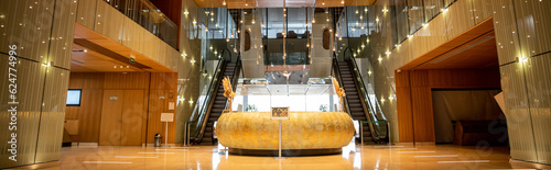 modern hotel interior with round reception desk and sophisticated lobby design, escalators, moving staircase, luxurious ambience, spacious and comfort, classy and chic, banner
