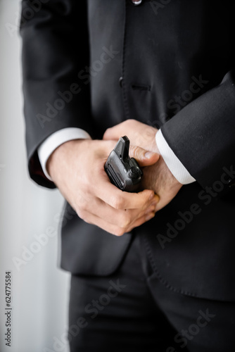 surveillance, cropped view of bodyguard standing with walkie talkie, man in black suit, hotel safety, security management, uniformed guard on duty, professional headshots