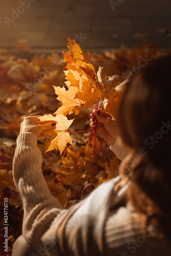 Women's hands hold yellow autumn leaves. View from above