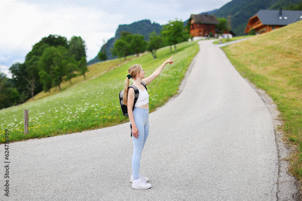Beautiful fit young woman hiking up a mountain and enjoying at the view on Alpine village Beautiful fit young woman hiking up a mountain and enjoying at the view on Alpine village
