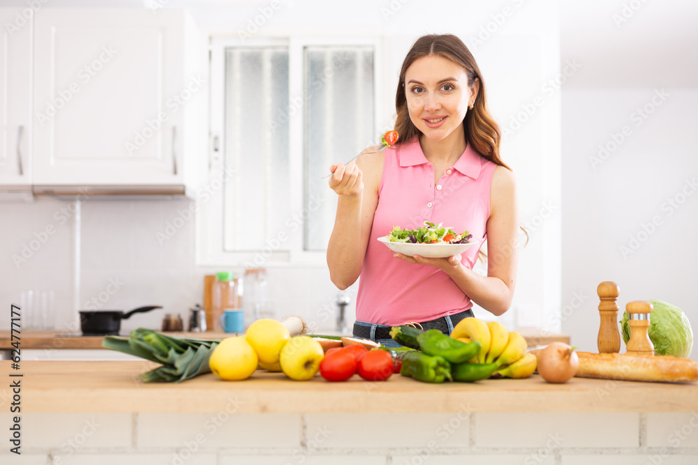 Cheerful woman eating vegetable salad at home Cheerful woman eating vegetable salad at home