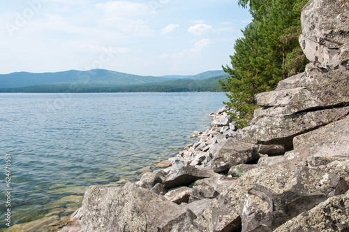 Landscape view of lake Turgoyak with boulders and pine trees on its shoreline, South Urals, Russian Federation