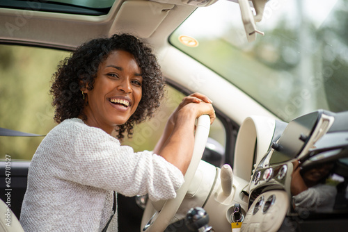 happy young african american woman driving in car