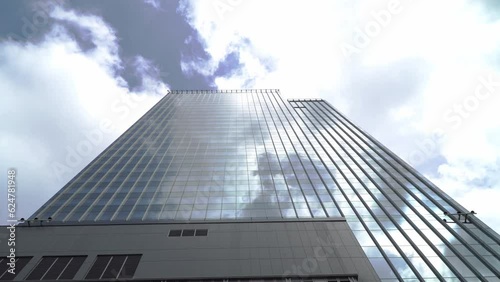 View of high rise glass building and dark steel window system on blue clear sky background.Business concept of future architecture,looking up to the sun light on the top of building