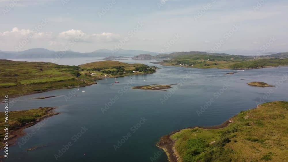 A high orbital done shot of the waterways between remote Scottish islands. Several small fishing boats can be seen in the background along with larger islands and the ocean. Shot on the Isle of Luing A high orbital done shot of the waterways between remote Scottish islands. Several small fishing boats can be seen in the background along with larger islands and the ocean. Shot on the Isle of Luing