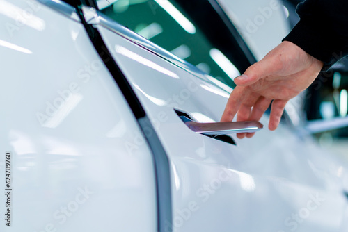 A man opens the door of his luxury white car after detailing and dry cleaning at a car service