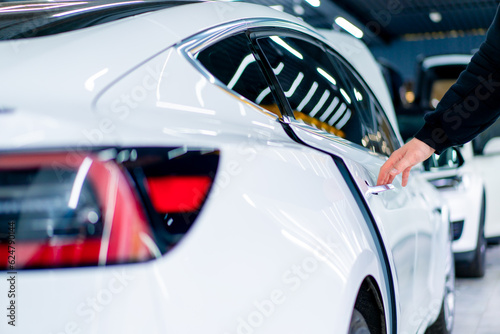 A man opens the door of his luxury white car after detailing and dry cleaning in a car service car rear view