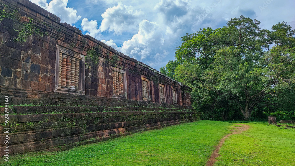 The beautiful of the green natural walkway side of sanctuary of Wat Phou Hindu vat Phou Temple complex is the UNESCO world heritage site in Champasak, Southern Laos at the blue cloud sky day.