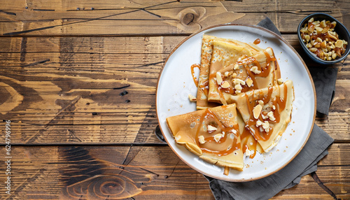 crepes with salted caramel and nuts, top view, wooden background, copy space photo