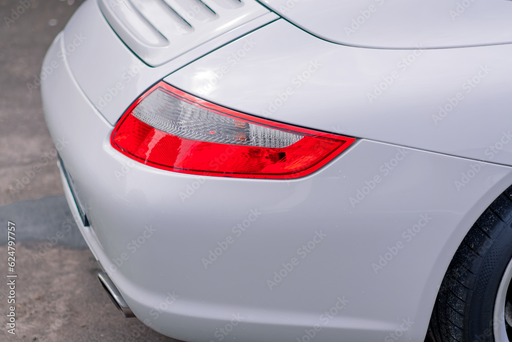 Detailing bumper and taillight of a white luxury car after washing at a car service station
