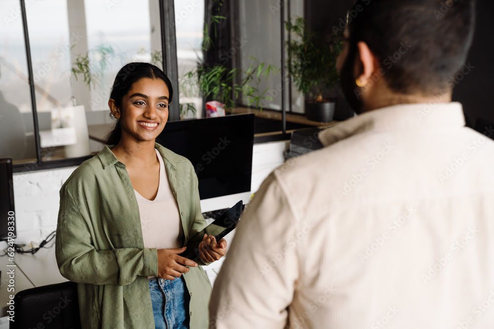 Obraz premium Indian business woman talking with her colleague while standing in office