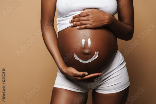 African pregnant girl smears smiling face on her stomach
